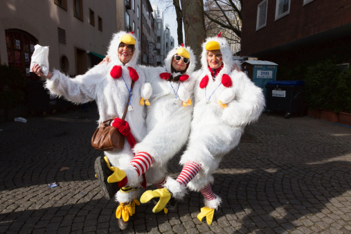 Cologne, Germany - February 27, 2014: Three women, all dressed as chicken, are dancing in the street of Cologne, celebrating the very special carnival day \