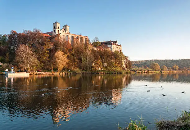 Benedictine monastery and on the rocky hill in Tyniec near Cracow, Poland, Vistula river and wild ducks in autumn at sunset.