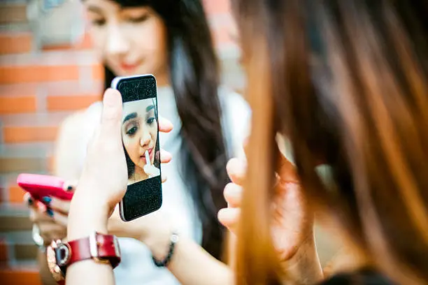 Photo of Japanese Teenage Girls using Smartphone as Vanity Mirror