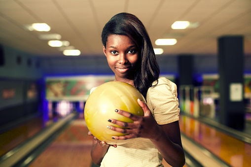 Smiling woman holding bowling ball at alley