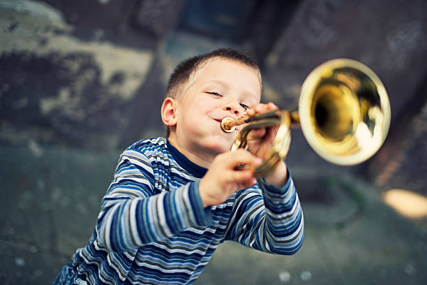 happy little boy playing trumpet - trompet stockfoto's en -beelden