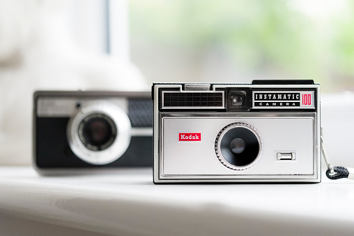 Kendal, UK - May 27, 2015: Close-up of the iconic Kodak Instamatic 100 from the 1960s, flanked in the defocussed background by a top of the range Instamatic 500.