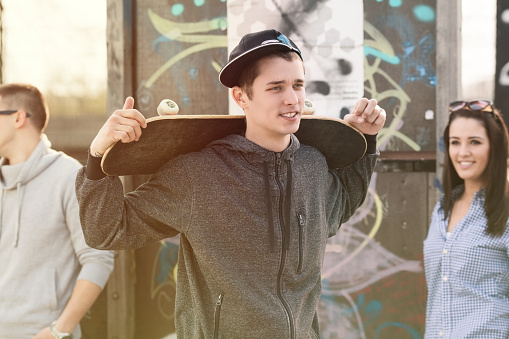 Cool teenage boy showing off in front of the girl in a skate park