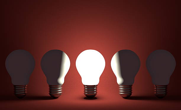 istock Glowing lightbulb in row of switched off ones on red 475989593