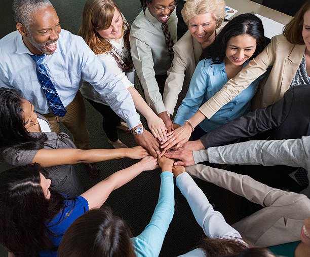 istock Diverse team of professionals with hands in teamwork huddle 475991154