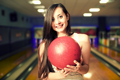 Smiling woman holding bowling ball at alley