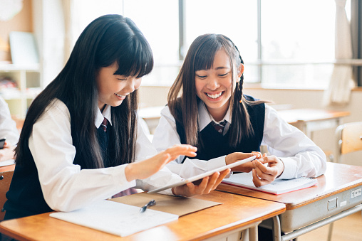 Japanese Junior High School Girl Students working together with digital tablet in classroom.