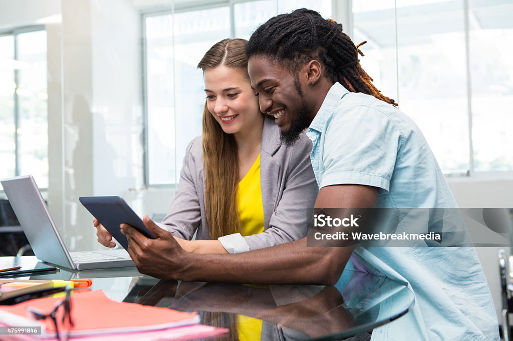 Creative young business people looking at digital tablet Creative young business people looking at digital tablet at office desk 20-24 Years Stock Photo