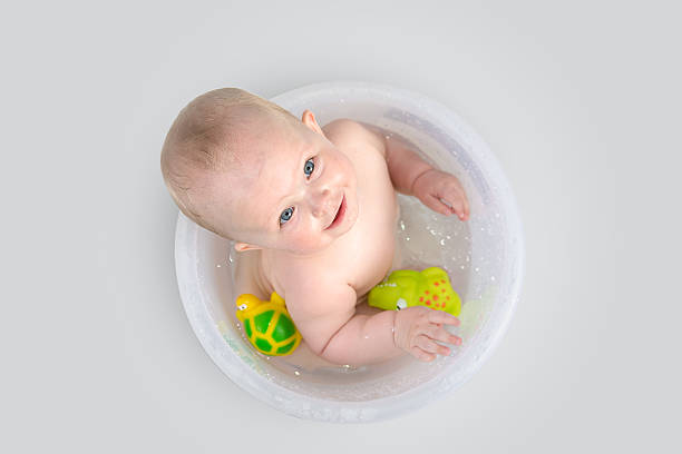Cute baby in transparent bucket and playing with toys stock photo