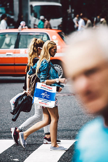Tokyo, Japan - May 16, 2015: Two caucasian women with tax free shopping bags crossing the streets in Akihabara district, also called Akihabara Electric Town.