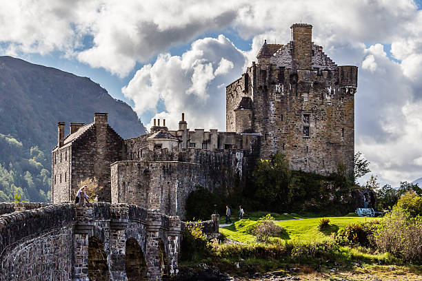 Eilean Donan Castle, Dornie, Scotland - September 20, 2014: eastern close-up in a sunny day with dramatic clouds backdrop. Tourists visit the historic building when touring Highland and Skye regions.