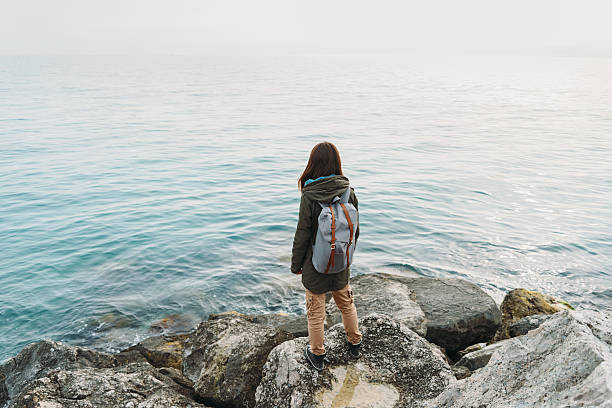 istock Woman standing on stone on coastline 475999042