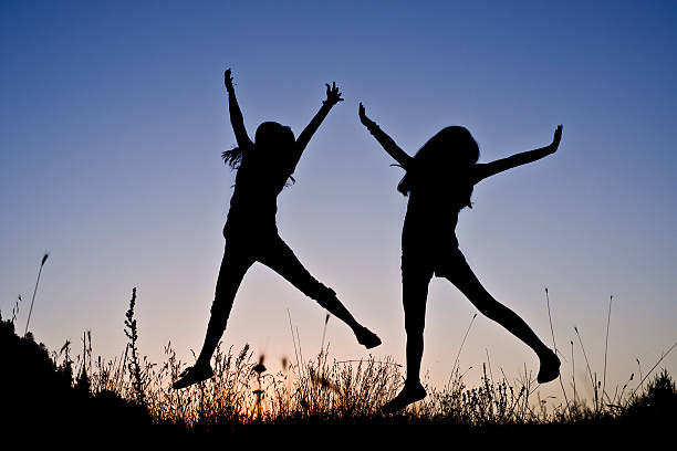 istock silhouette of friends jumping in sunset 476001775