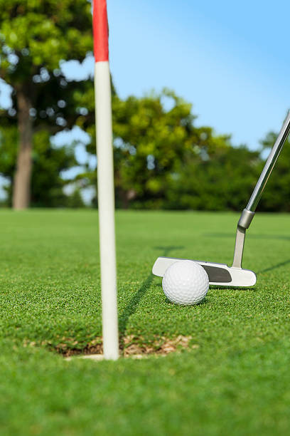 istock putter puts a golf ball to hole on green 476004726