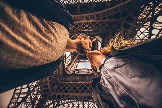 Under the Eiffel Tower Young loving couple kissing under the Eiffel tower in Paris, France. paris france eiffel tower love kissing stock pictures, royalty-free photos & images