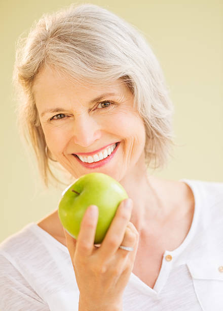 feliz mujer agarrando manzana granny smith - apple women green eating fotografías e imágenes de stock