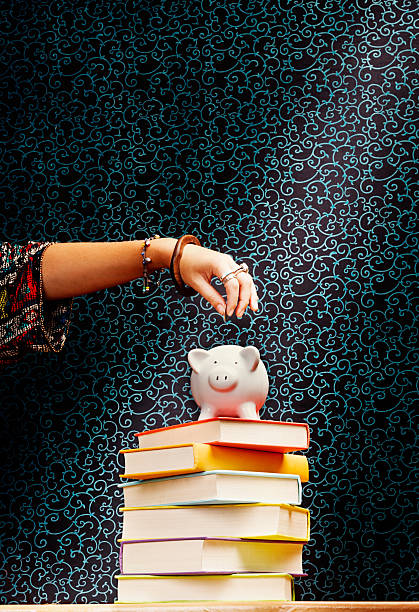 istock Saving for an education: hand adding coins to piggybank 476009199