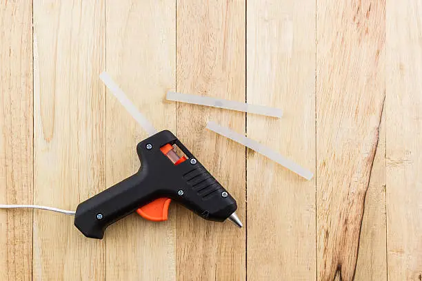 Electric hot glue gun on a wood background.