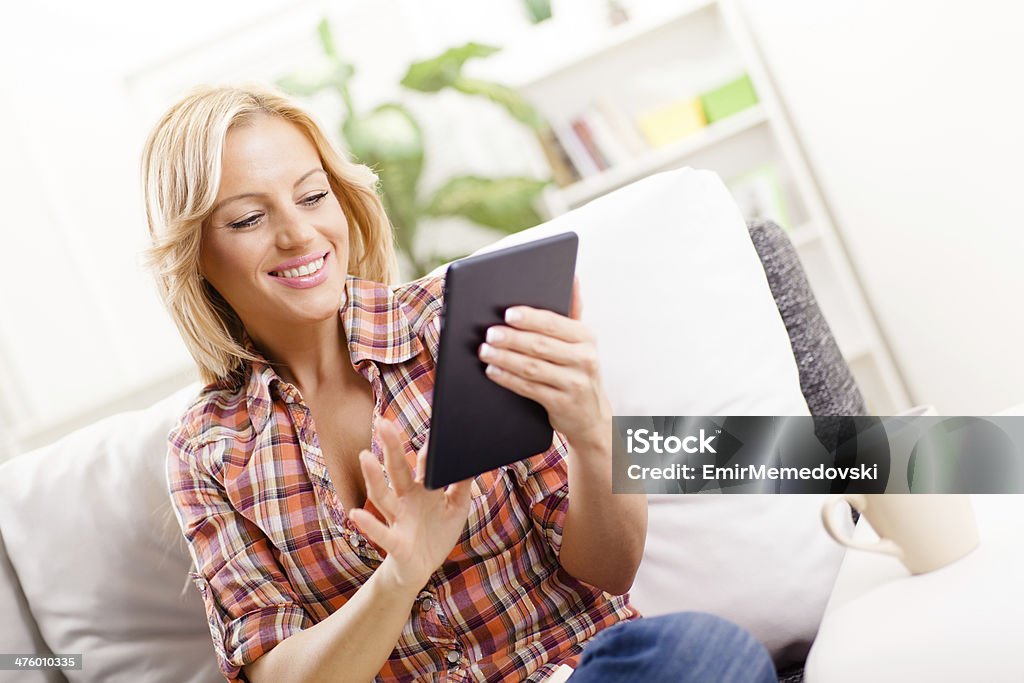 Jovem mulher olhando no tablet digital na sala de estar - Foto de stock de Aconchegante royalty-free