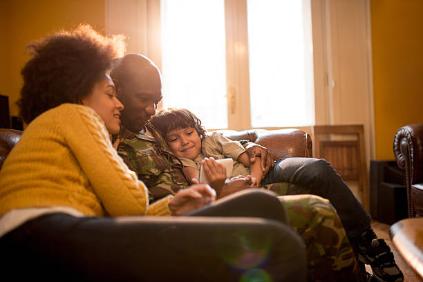 African American military family using cell phone at home. Happy military family relaxing at home and using smart phone together. military lifestyle stock pictures, royalty-free photos & images