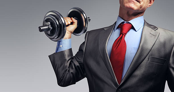 Image of businessman in suit raising dumbbell. Tax burden concept stock photo