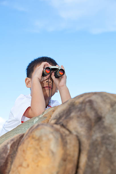 istock Happy little boy exploring outdoors clambering on rock with telescope. 476019274