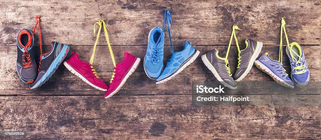 Running shoes on the floor Five pairs of various running shoes hang on a nail on a wooden fence background Sports Shoe Stock Photo