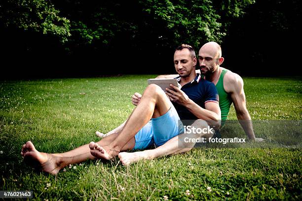 Atractiva Pareja Gay Descanse En Un Parque Foto de stock y más banco de imágenes de Adulto - Adulto, Aire libre, Amor - Sentimiento