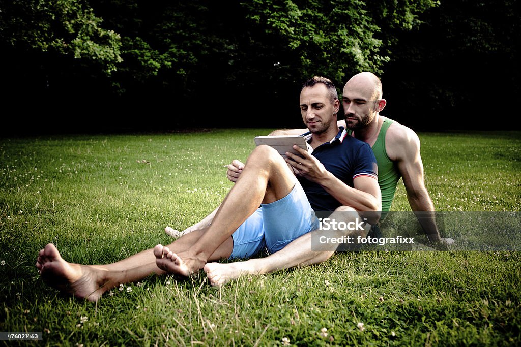 Bella coppia gay rilassarsi in un parco - Foto stock royalty-free di Abbigliamento casual