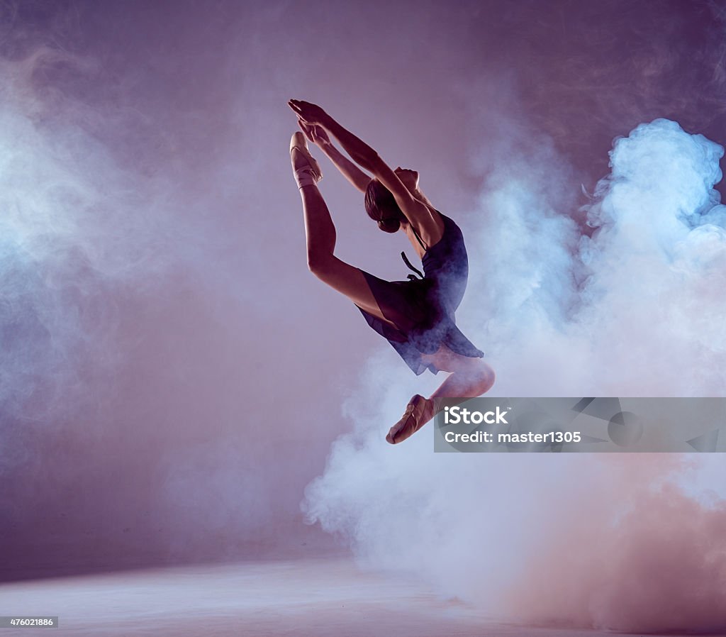 Beautiful young ballet dancer jumping on a lilac background young ballet dancer jumping on a lilac background. Ballerina is wearing in blue dress and pointe shoes. The outline shooting - silhouette of girl with smoke effect Dancing Stock Photo