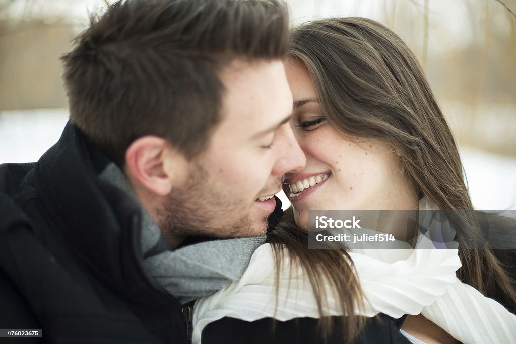 Young couple being affectionate in winter Attractive heterosexual couple kissing on a blanket in the snow Couple - Relationship Stock Photo