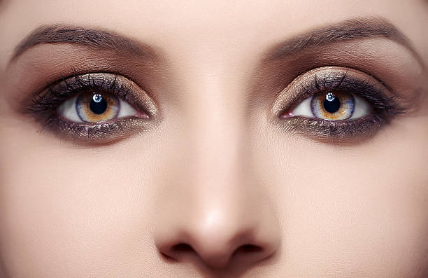 woman with blue and hazel eyes front view of part of woman face, blue and hazel eyes, looking intense at camera. hazel blue eyes stock pictures, royalty-free photos & images
