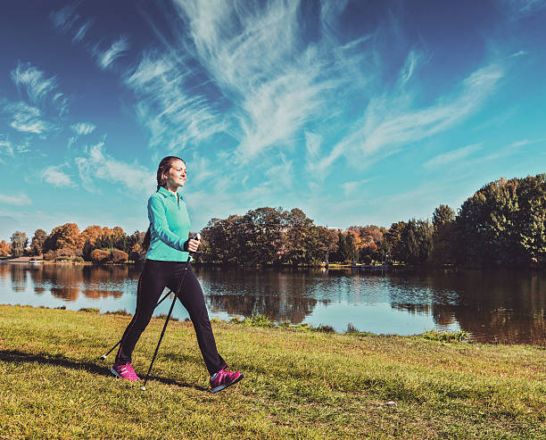 młoda kobieta nordic walking - nordic walking zdjęcia i obrazy z banku zdjęć