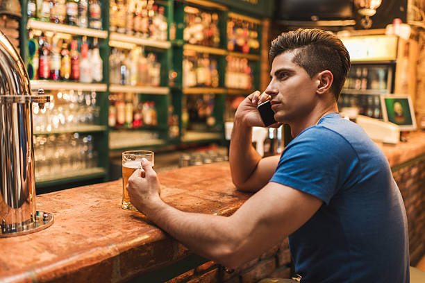 istock Pensive man sitting in bar and talking on cell phone. 476028036