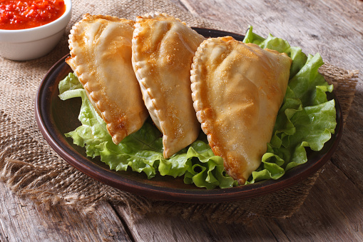 pies empanadas on a plate with lettuce and sauce closeup. horizontal