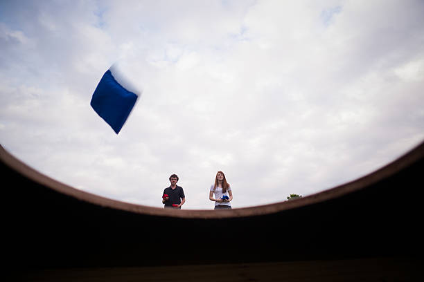 Boy and girl playing beanbag toss at park stock photo