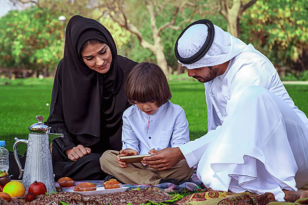 istock Young Arabic family using digital tablet at park 476037100