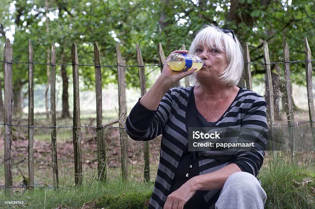Senior Frau trinkt Flasche Limonade gegen Zaun - Lizenzfrei Aktiver Senior Stock-Foto