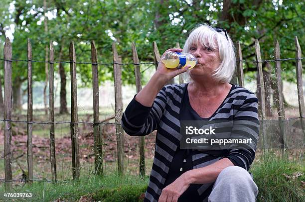 Senior Donna Bere Una Bottiglia Di Limonata Contro La Parete - Fotografie stock e altre immagini di Adulto