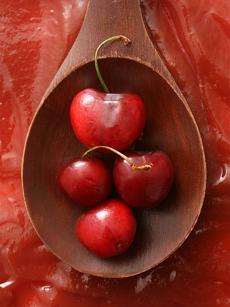 Cherries and jam Top view of wooden spoon with fresh cherries over it and jam beneath it healthy eating red above studio shot stock pictures, royalty-free photos & images