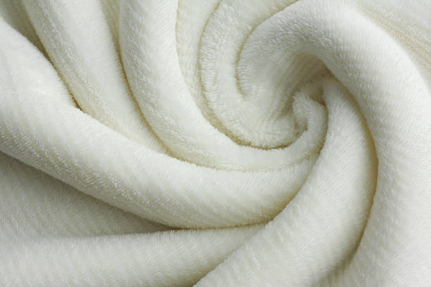 Soft White Blanket Swirl Background a soft white, plush micro fleece blanket is swirled into a circular pattern background fluffy blanket stock pictures, royalty-free photos & images