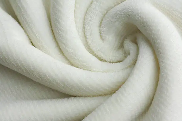 a soft white, plush micro fleece blanket is swirled into a circular pattern background