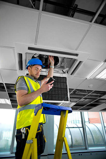 istock electrician fitting air conditioning to office interior 476046459
