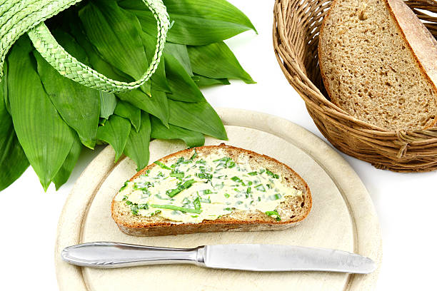 herb butter ramson (Allium ursinum) on bread cutting wild garlic leaves for herb butter. in background a bag with ramson leafs. white isolated background zigeunerlauch stock pictures, royalty-free photos & images