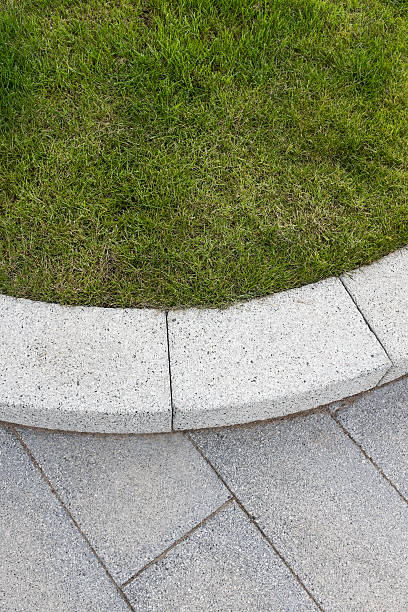 istock Grey stone paving & kerb adjacent to green grass lawn 476053748