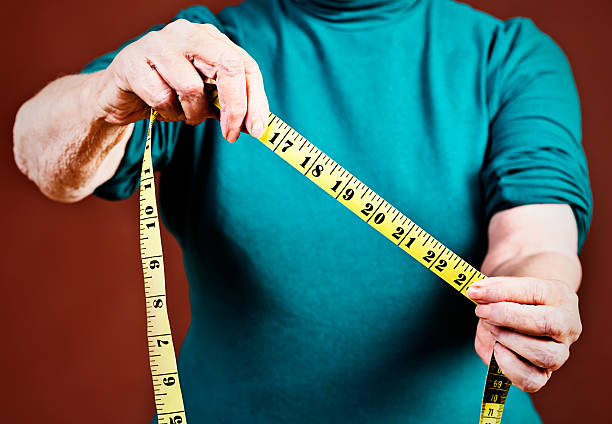 istock Do you measure up? Old hands hold out measuring tape 476071199
