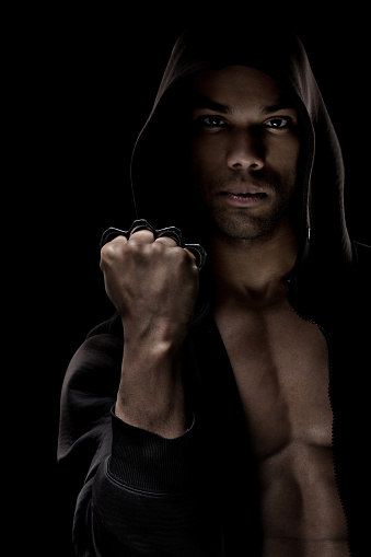 Muscular black hooded male posing with a knuckle duster 