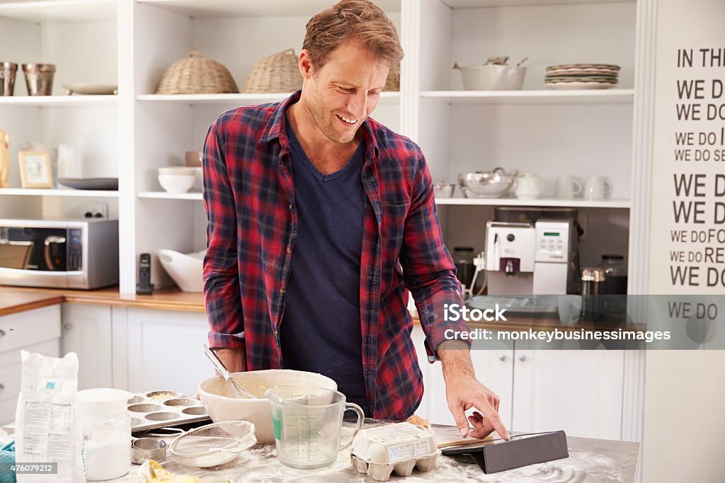 Middle aged man reading recipe on tablet computer Baking Stock Photo
