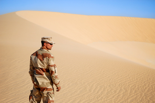 Chad,Rahel, Sahara - December 14, 2012: The picture was took middle of the desert of chad, during a morning time, we can see a french soldier man from troupes of marine, he wear a desert uniform and sunglasses, alone, he is looking around him, trying to find some water. December 2010
