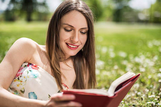 istock Smiling woman reading a book during springtime in nature. 476084858
